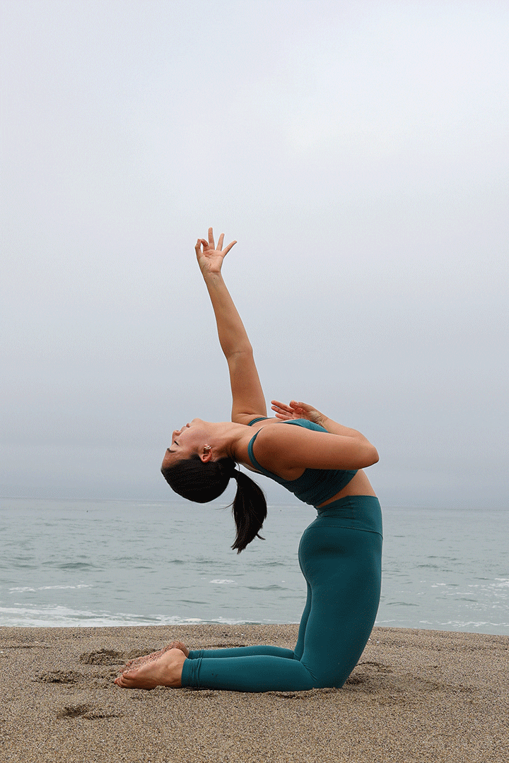 A woman doing yoga on the beach.