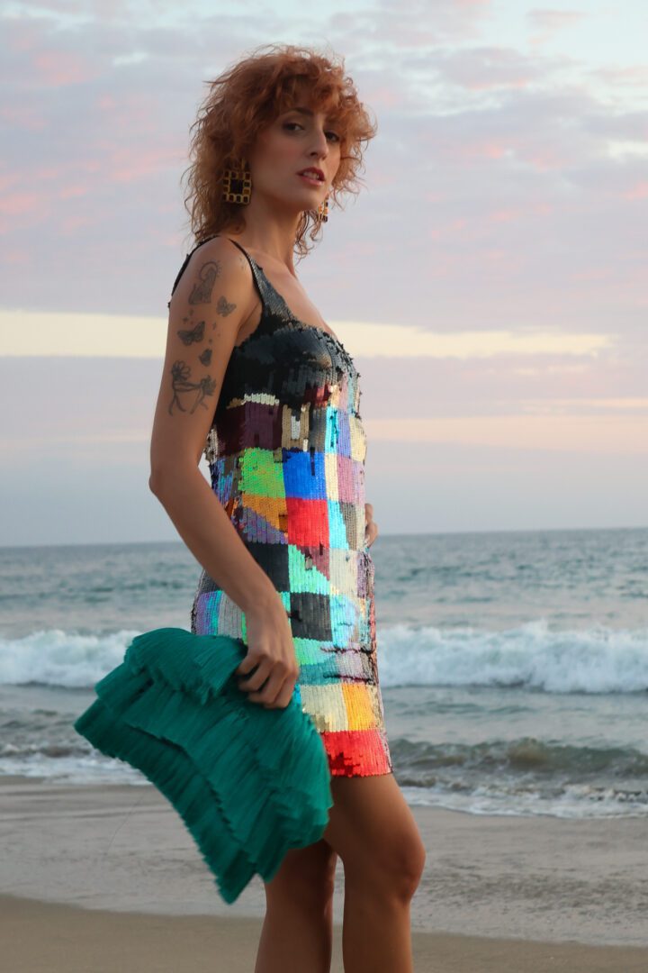 A woman in a colorful dress standing on the beach.