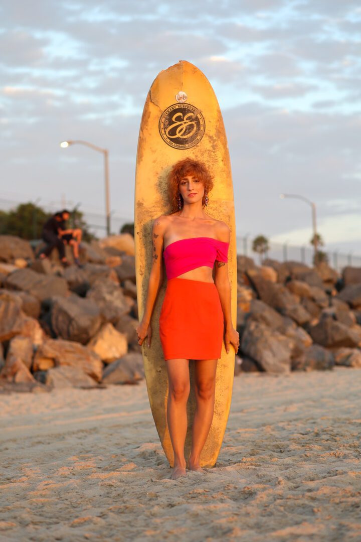 A woman standing on a beach with a surfboard.