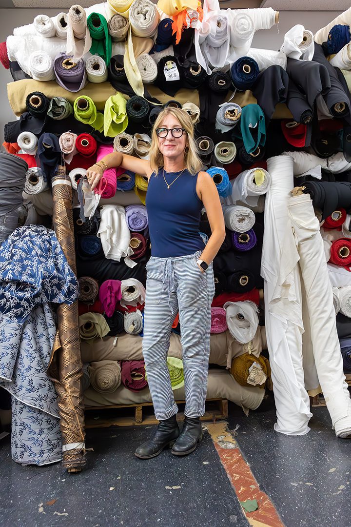 A woman standing in front of a pile of fabric.
