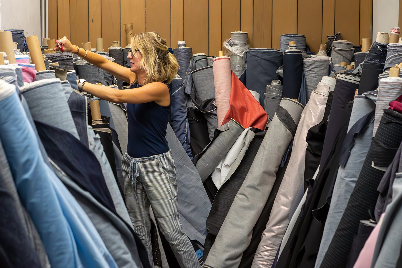 A woman is standing in a room full of fabric.