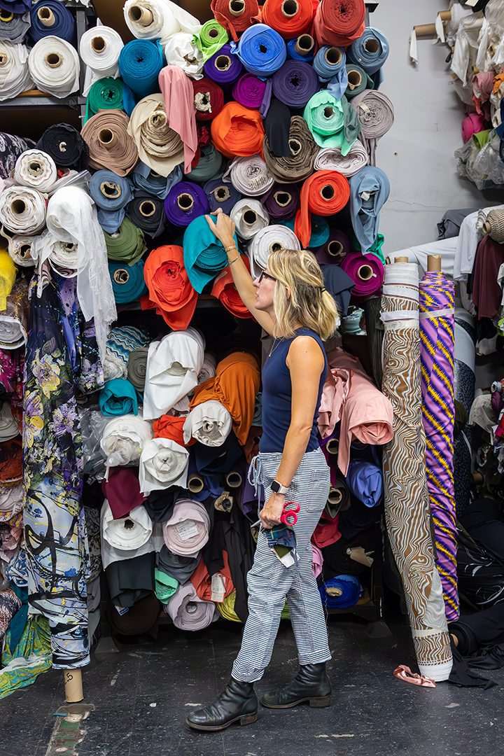 A woman standing in front of a large pile of fabric.