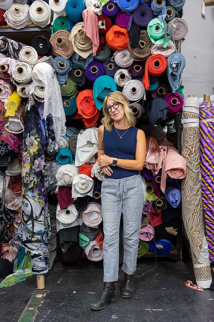 A woman standing in front of a lot of fabric.