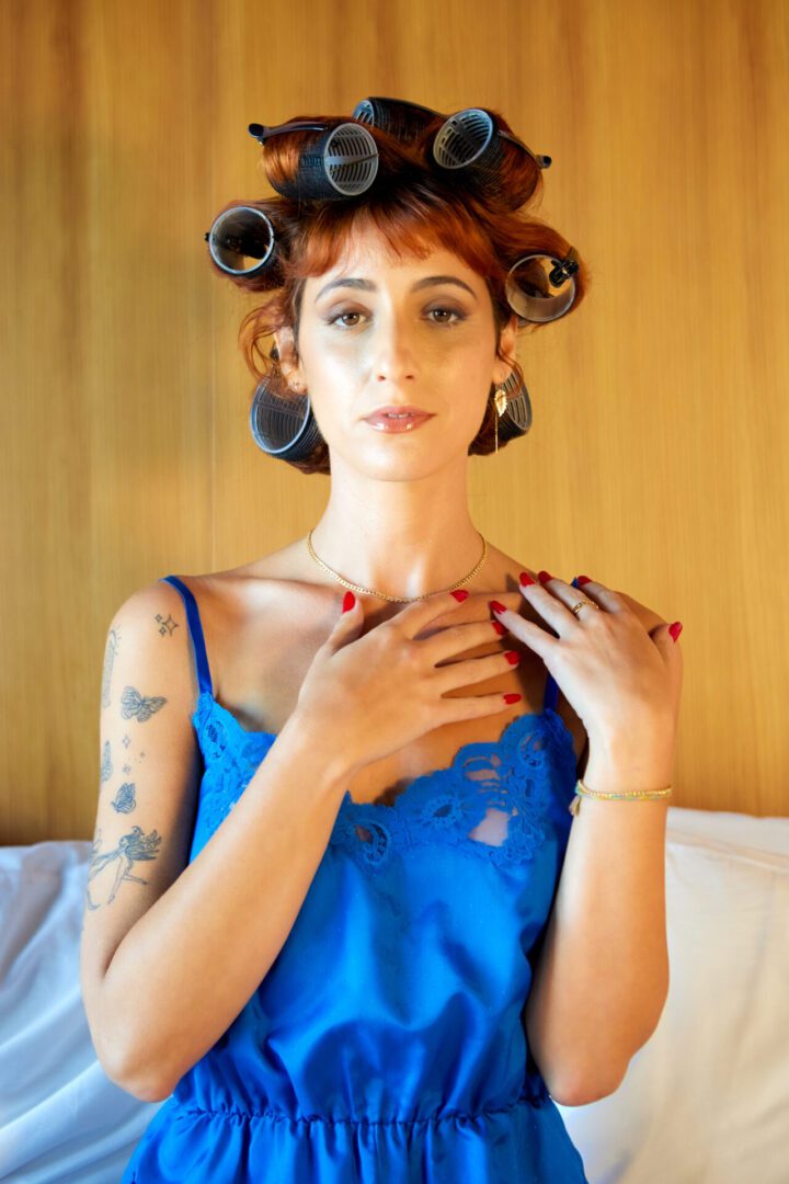 A woman in a blue dress with curlers on her head.