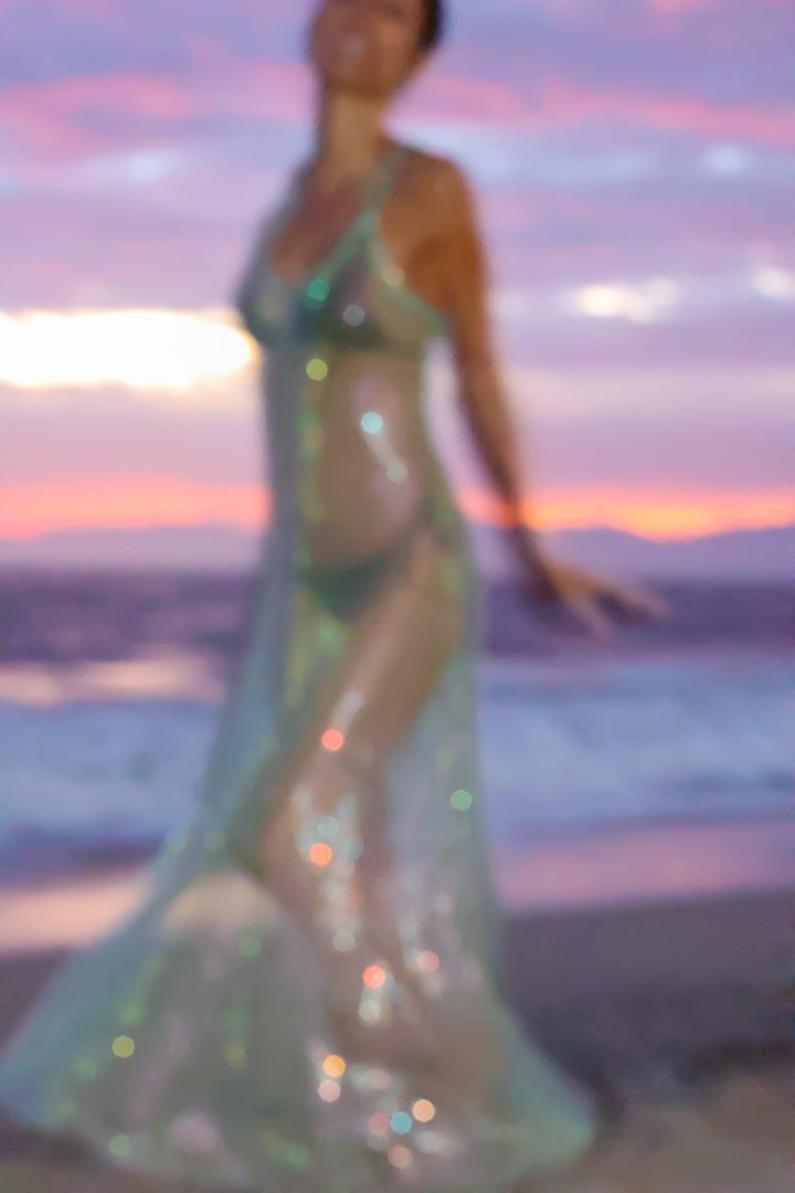 A woman in a long dress on the beach.