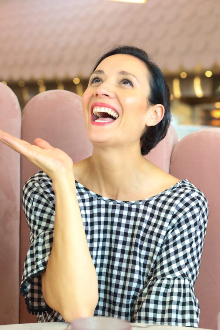 A woman laughing while sitting at a table in a restaurant.