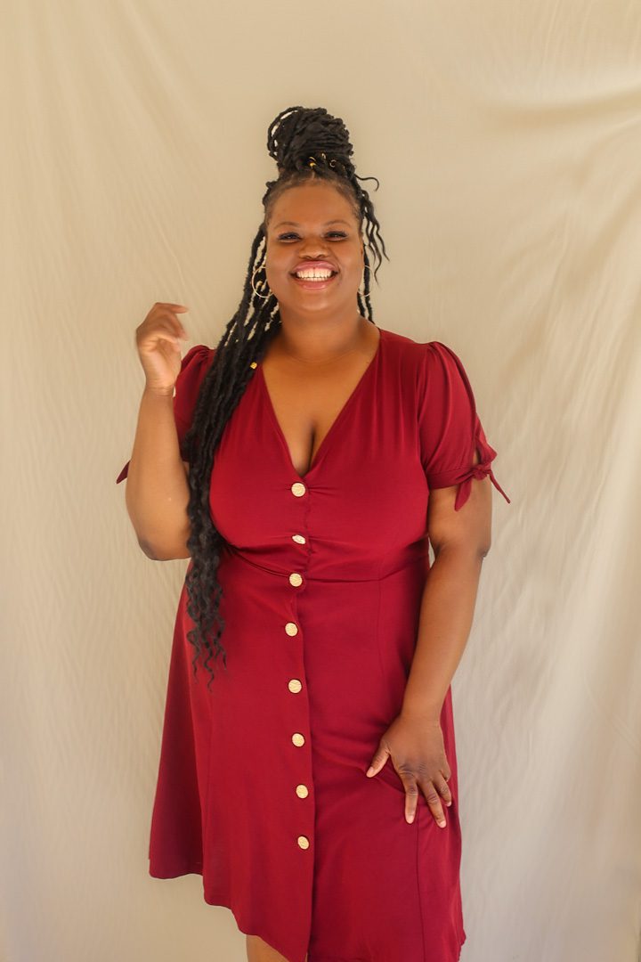 A woman in a burgundy dress posing for a photo.