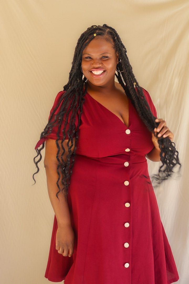 A black woman in a red dress posing for a photo.